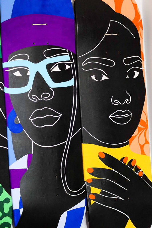 Three skateboard decks with artistic faces and colorful backgrounds